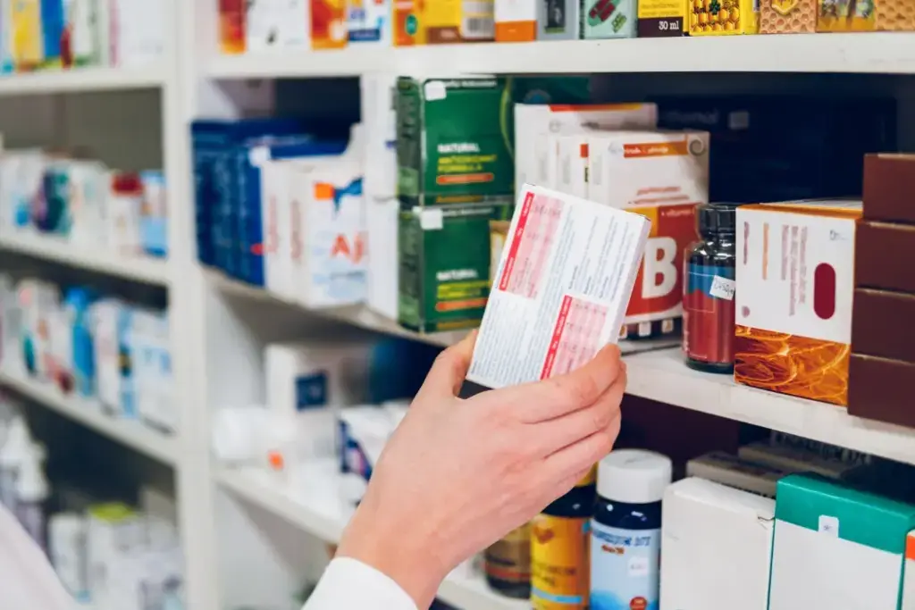 A pharmacist grabs a box of medication for a customer.
