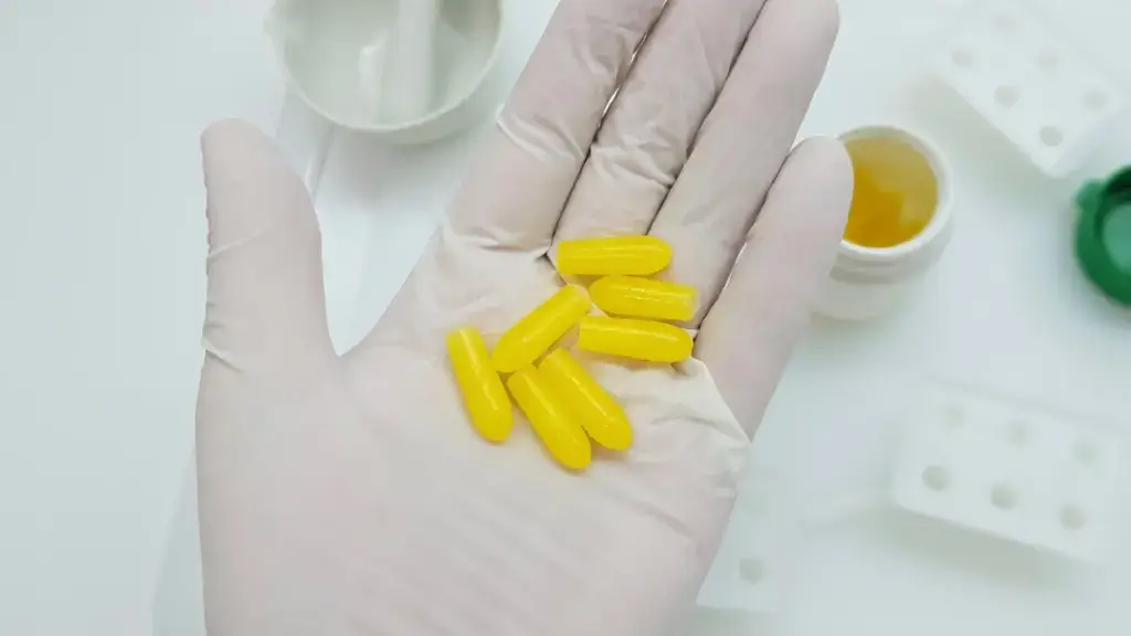 Yellow Capsules in a gloved hand.